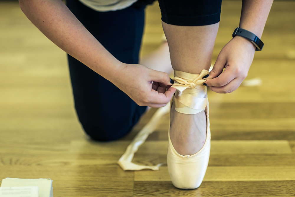 A dancer tying a ballet pointe shoe at AVDC